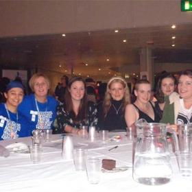 A group of people sat at a table with glasses and a water jug on it.