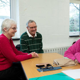 People smiling and sitting around a table having a chat