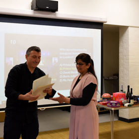 Presenters in front  of a large screen looking at papers