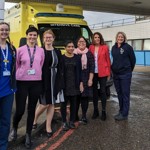 Seven members of staff in front of an ambulance outside the "Women's Centre Maternity" entrance