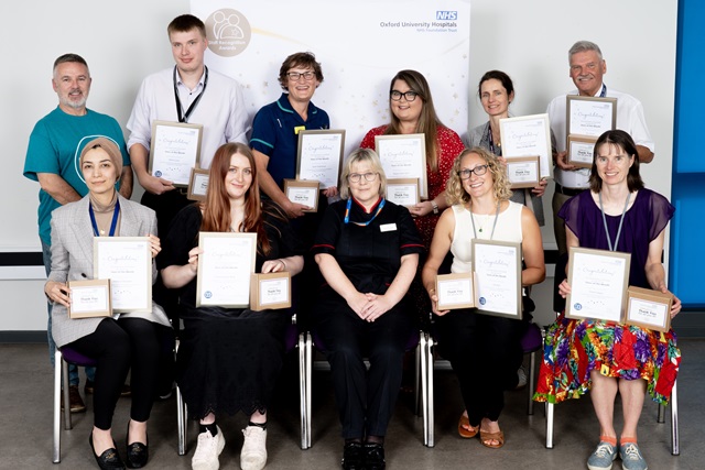 11 people in front of an 'Oxford University Hospitals' banner. 9 hold their certificates and awards.