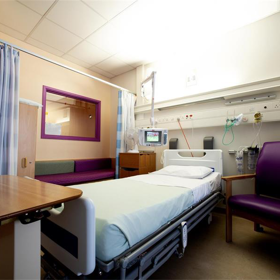 An empty patient cubicle with a bed made.