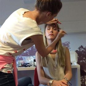 Someone sat in a chair having eye make-up applied.