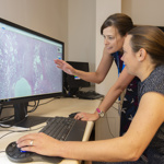 Two women look at a digital pathology image on a screen