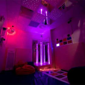 A dark room with coloured lights and sensory equipment.