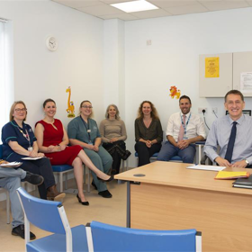 Staff members sit smiling around a bright clinic room.