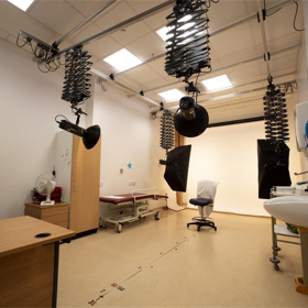 A room with hanging lights and a chair, ready for a photography sitting.