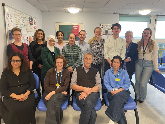 Group of 14 people. Four are sat down, with the rest stood behind