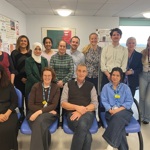 Group of 14 people. Four are sat down, with the rest stood behind