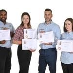 Four members of staff hold their certificates
