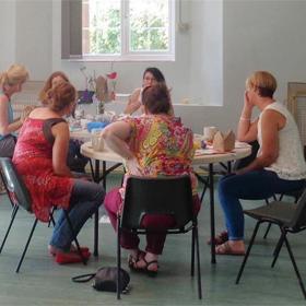 A group of people sat around two tables, talking.