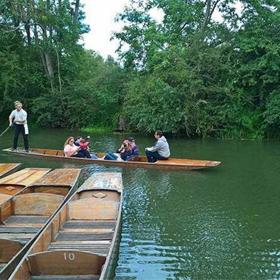 A group of people in a boat, punting.