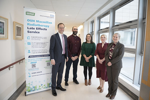 Jan Bornschein, Mitch Sharman-Else, Rebecca Shakir, Loidalyn Sparkes, Marios Spindler and Sinead Sullivan standing in a hospital corridor by a Late Effects Service banner