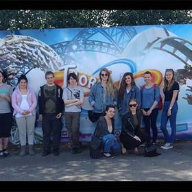 A group of people standing in front of a sign with a rollercoaster on it.