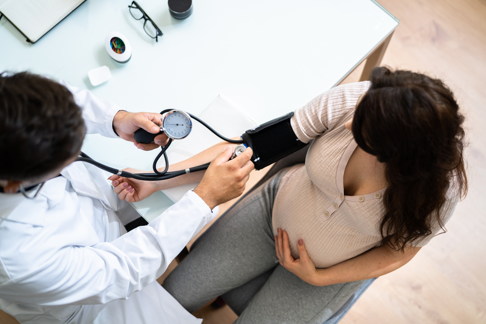 doctor measuring blood pressure of pregnant woman 