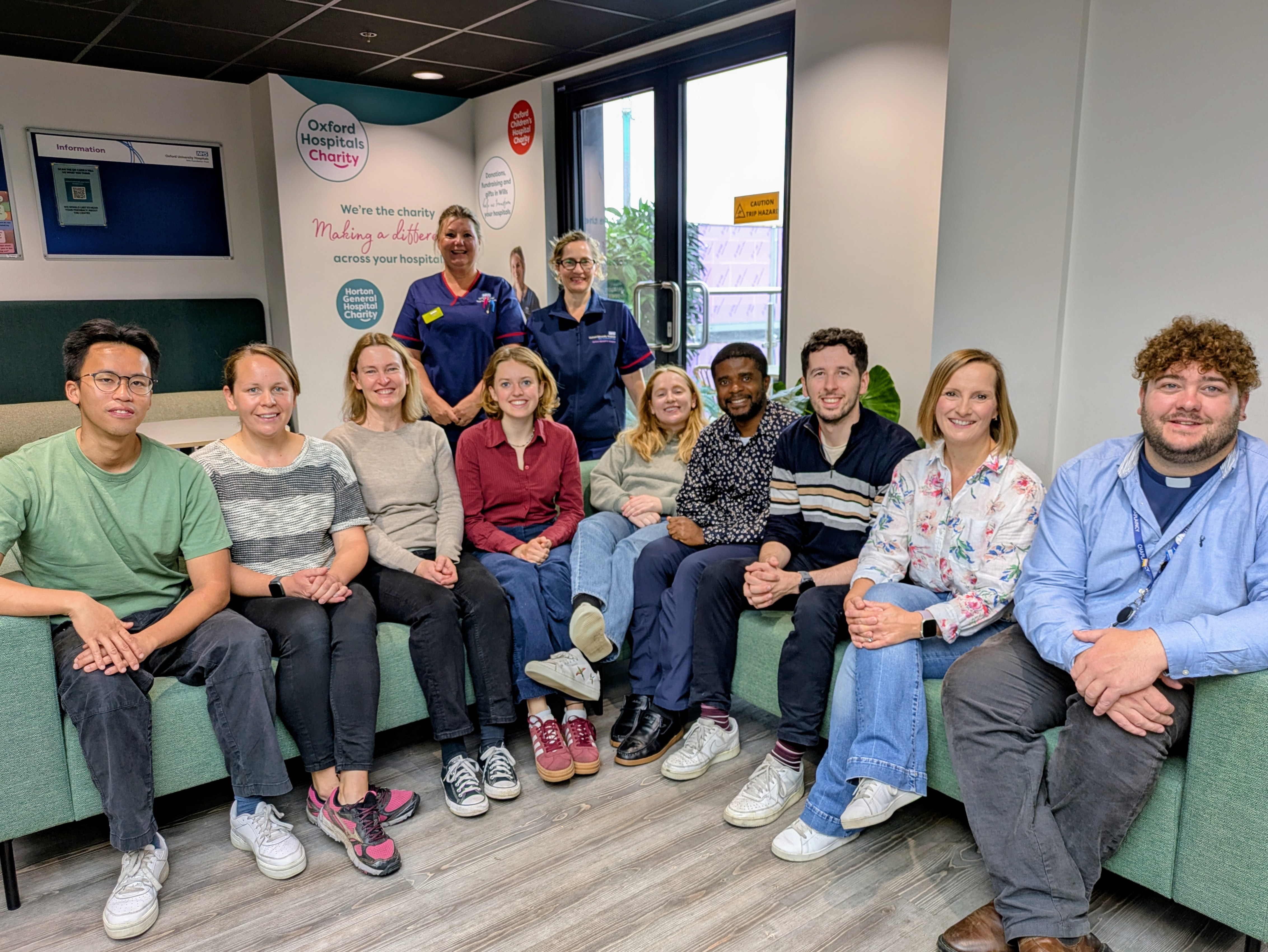 group of CNO fellows and BRC interns sitting on a sofa, with senior nurses standing behind   
