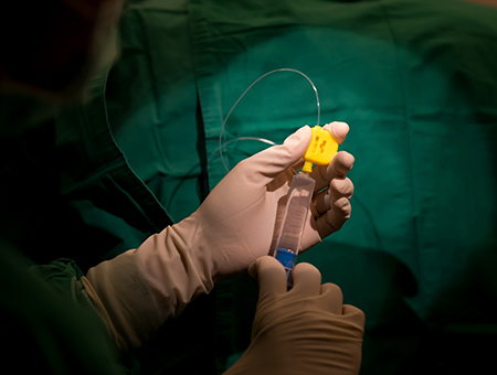 Gloved hands attach syringe to a tube