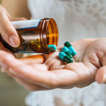 Hands tipping pills from a container