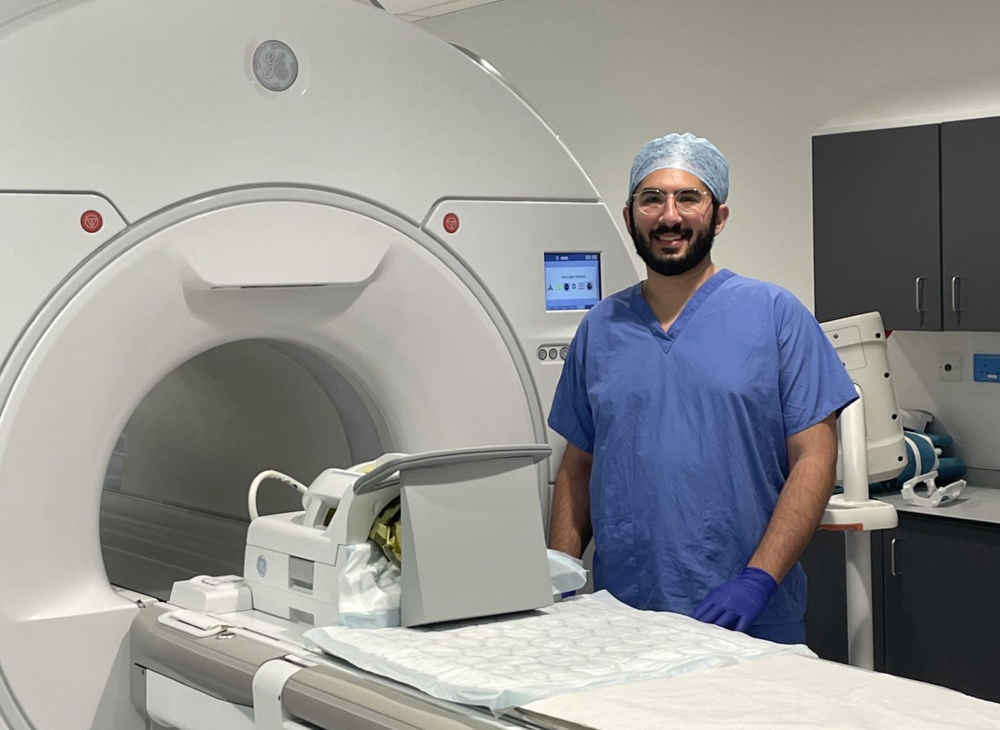 doctor in scrubs standing by an MRI machine