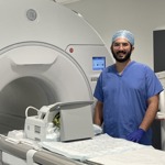 doctor in scrubs standing by an MRI machine