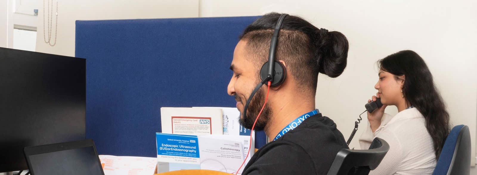 Young man in headset and young woman speaking on the telephone, both smiling