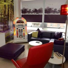 Room with sofa, chair, foot stool, side tables, jukebox and tv.